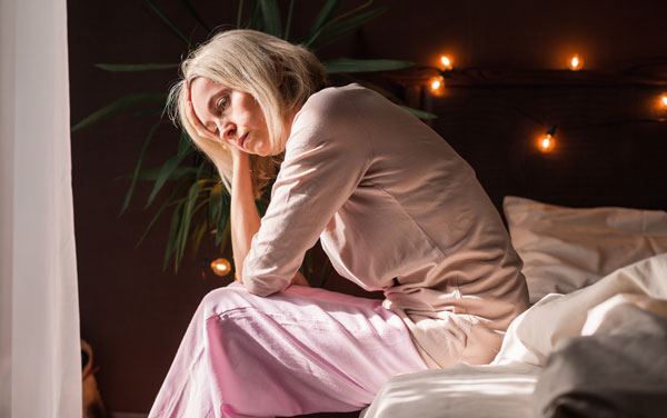 Tired woman sitting on bed