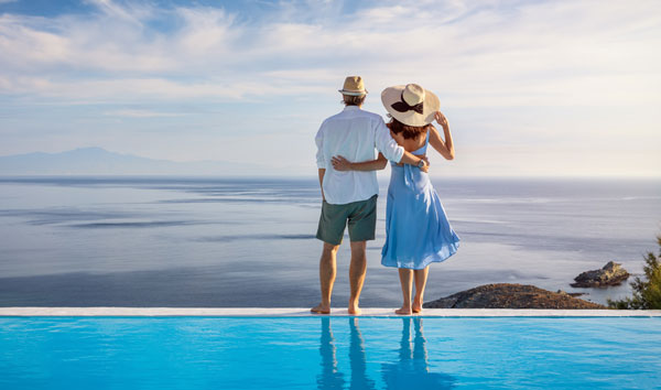 Couple standing by a pool looking out over the ocean